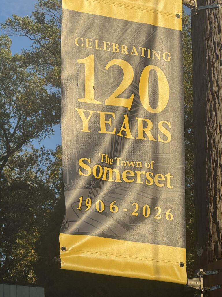 Banner celebrating the Town of Somerset's 120th anniversary, 1906–2026, hanging from a utility pole among trees.