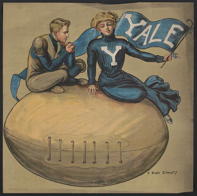 A man and woman sit atop an oversized Yale football while the woman waves a Yale pennant.
